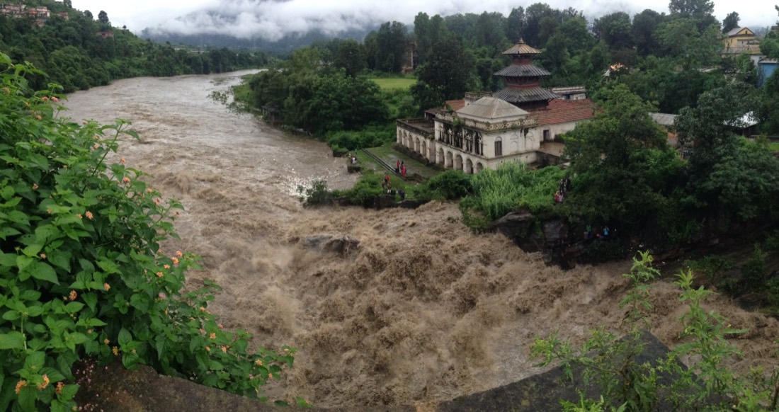 The Bagmati River in monsoon flood beside a riverside temple, Kathmandu